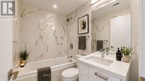 Toronto (Moss Park) condo for rent - A bathroom with marble walls and a white countertop.