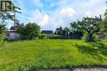 Windsor apartment for rent - A grassy field with a wooden fence and trees in the background.