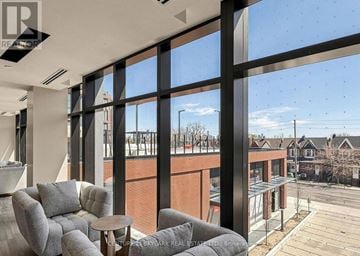 Toronto (Dovercourt-Wallace Emerson-Junction) condo for rent - A living room with a grey sofa and a large window overlooking a street.