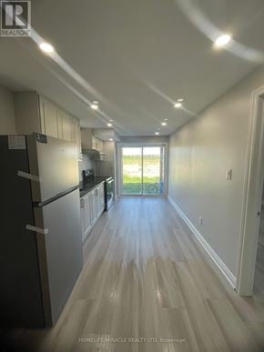 Barrie apartment for rent - A long hallway with a refrigerator on the left and a doorway leading to a balcony on the right.