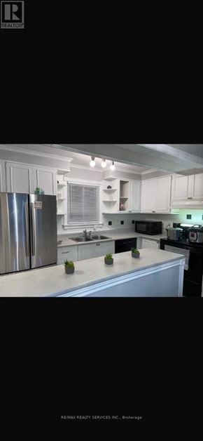 Brampton (Central Park) apartment for rent - A kitchen with white cabinets and a stainless steel refrigerator.