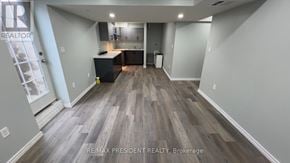 Kitchener apartment for rent - A spacious room with wooden flooring and a kitchen area in the background.