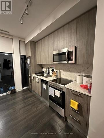 Toronto (Church-Yonge Corridor) condo for rent - A modern kitchen with dark wood floors and stainless steel appliances.