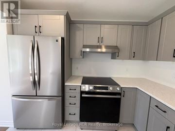 Grey Highlands townhouse for rent - A kitchen with a stainless steel refrigerator and a stove top oven.