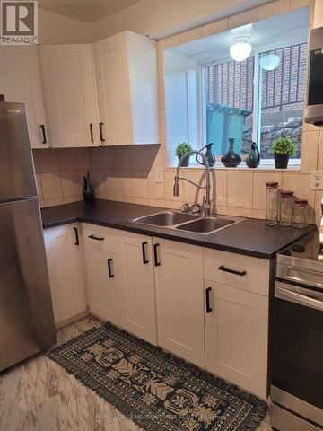 Hamilton (Huntington) multi-family for rent - A kitchen with white cabinets and a black and white rug on the floor.