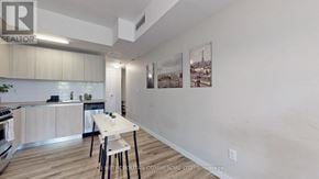 Toronto (Kensington-Chinatown) condo for rent - A kitchen with a dining table and chairs in the foreground and a wall with pictures hanging on it.