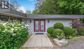 Adjala-Tosorontio apartment for rent - A house with a red door surrounded by greenery and flowers.