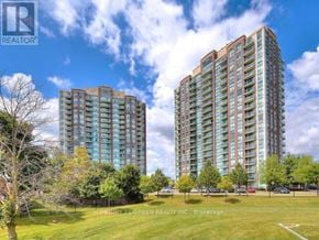 Mississauga (Central Erin Mills) condo for rent - Two tall apartment buildings are surrounded by a grassy field.