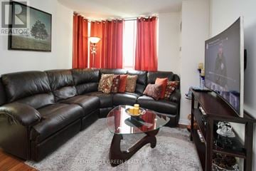 Mississauga (Central Erin Mills) condo for rent - A living room with a black leather couch and a glass coffee table.