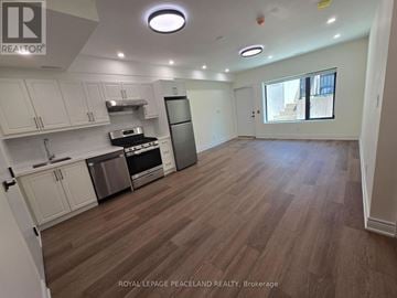 Toronto (University) multi-family for rent - A kitchen with white cabinets and a wooden floor.