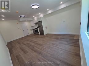 Toronto (University) multi-family for rent - A room with wooden flooring and a refrigerator in the corner.