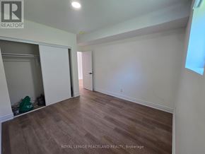 Toronto (University) multi-family for rent - A room with wooden flooring and white walls, with a doorway leading to another room.