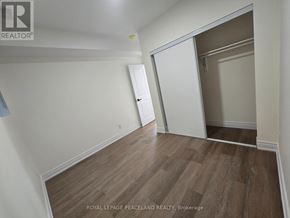 Toronto (University) multi-family for rent - A room with wooden flooring and white walls, with a door on the right side.