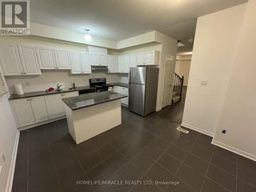 Ajax (Central) townhouse for rent - A kitchen with white cabinets and a black countertop.