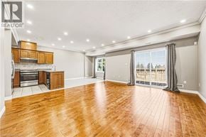 Hamilton townhouse for rent - A spacious room with wooden flooring and a kitchen area with stainless steel appliances.