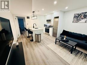 Toronto (Caledonia-Fairbank) apartment for rent - A modern living room with a black couch and a kitchen area in the background.