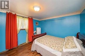 Niagara Falls (Dorchester) apartment for rent - A bedroom with a bed, a window with red curtains, and a white wall.