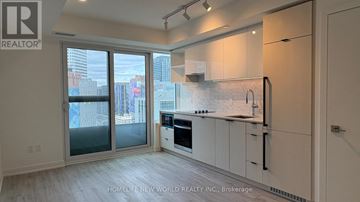 Toronto (Church-Yonge Corridor) condo for rent - A modern kitchen with white cabinets and a view of the city.