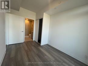 Toronto (South Parkdale) condo for rent - A room with wooden flooring and white walls, with a doorway leading to another room.