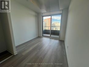 Toronto (South Parkdale) condo for rent - A room with wooden flooring and a view of a city skyline through a sliding glass door.