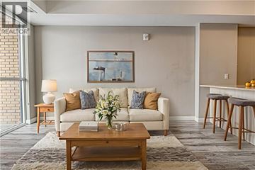 Kitchener condo for rent - A living room with a white couch, a wooden coffee table, and a painting on the wall.
