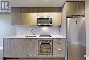 Toronto (Henry Farm) condo for rent - A kitchen with a stainless steel refrigerator and wooden cabinets.