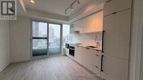 Toronto (Church-Yonge Corridor) condo for rent - A spacious kitchen with white cabinets and a marble backsplash.