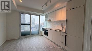 Toronto (Church-Yonge Corridor) condo for rent - A spacious kitchen with white cabinets and a marble backsplash.