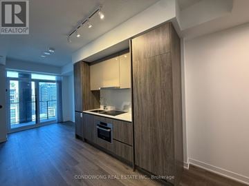 Toronto (Moss Park) condo for rent - A modern kitchen with wooden cabinets and a large window.