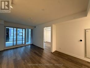 Toronto (Moss Park) condo for rent - A spacious room with wood flooring and white walls.