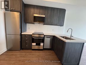 Clarington (Bowmanville) condo for rent - A kitchen with dark wood cabinets and a stainless steel refrigerator.