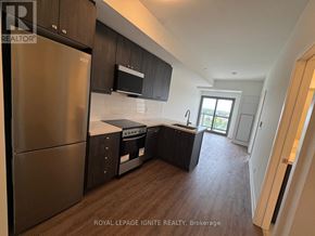 Clarington (Bowmanville) condo for rent - A kitchen with a refrigerator, microwave, and oven.
