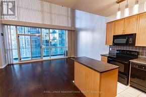 Mississauga (City Centre) condo for rent - A kitchen with wooden cabinets and a black countertop.