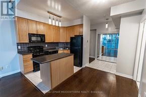 Mississauga (City Centre) condo for rent - A kitchen with wooden cabinets and black appliances.