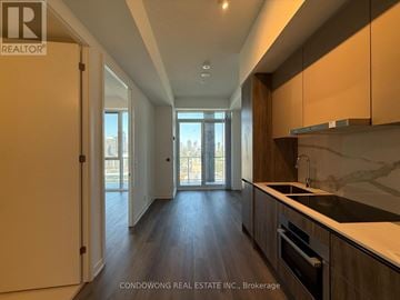 Toronto (Moss Park) condo for rent - A modern kitchen with dark wood floors and a marble countertop.