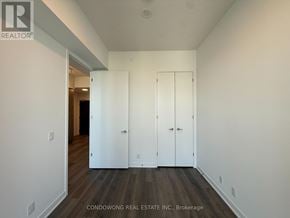 Toronto (Moss Park) condo for rent - A hallway with white walls and wood flooring, with two white doors on the right side.