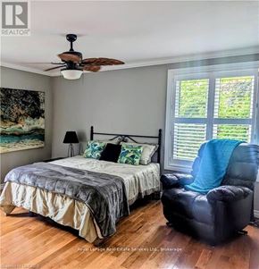 Hamilton (Waterdown) apartment for rent - A bedroom with a bed, chair, and painting.