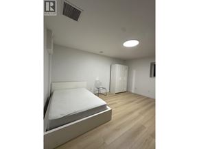Burnaby townhouse for rent - A bedroom with a bed, nightstand, and lamp.