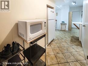 Vancouver apartment for rent - A white microwave is on a black stand in a room with a tiled floor.