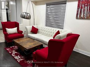 Brampton (Fletcher's Creek Village) apartment for rent - A living room with a white sofa, red armchairs, and a wooden coffee table.