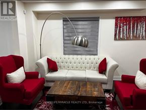Brampton (Fletcher's Creek Village) apartment for rent - A living room with a white sofa, red armchairs, and a wooden coffee table.