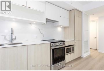 Toronto (Church-Yonge Corridor) condo for rent - A modern kitchen with white cabinets and a stove top oven.