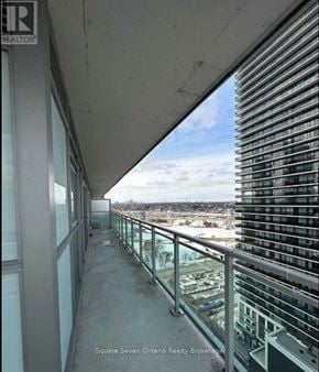 Toronto (Mimico) condo for rent - A balcony with a glass railing and a view of a cityscape.