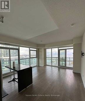 Toronto (Mimico) condo for rent - A spacious room with a view of the cityscape through large windows.
