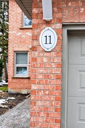Oakville (Ro River Oaks) townhouse for rent - A red brick house with a grey door and a white number 11 on the wall.