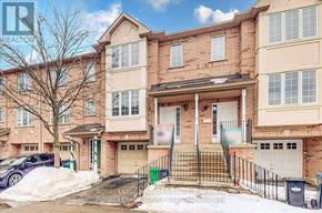 Mississauga (Hurontario) townhouse for rent - A large brick apartment building with a black fence and a white garage door.