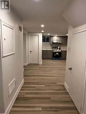 Brampton (Brampton East) apartment for rent - A hallway with white walls and wood flooring leads to a kitchen area.
