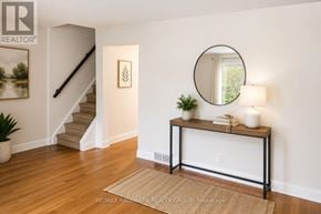 Ottawa townhouse for rent - A room with a staircase, a table with a plant, and a round mirror on the wall.