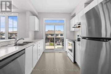 Ottawa townhouse for rent - A modern kitchen with white cabinets and stainless steel appliances.
