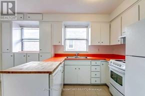 Toronto (Bedford Park-Nortown) apartment for rent - A kitchen with white appliances and cabinets with a red backsplash.